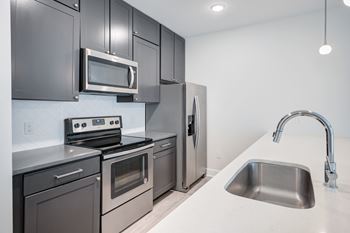 A modern kitchen with a stainless steel refrigerator, oven, and microwave.